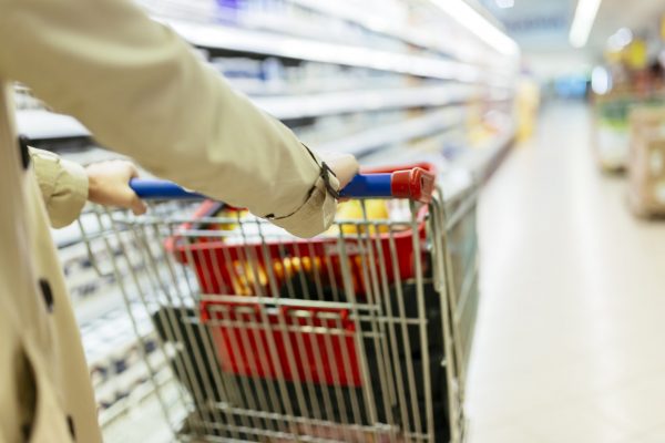 Woman pushing shopping trolley Woman pushing shopping trolley in modern supermarket